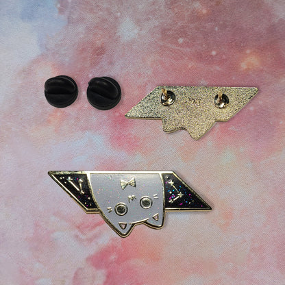 Metallic cat-shaped pin with black accents on a pink and purple background